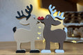 Dúo de figuras decorativas de renos navideños que se besan.
